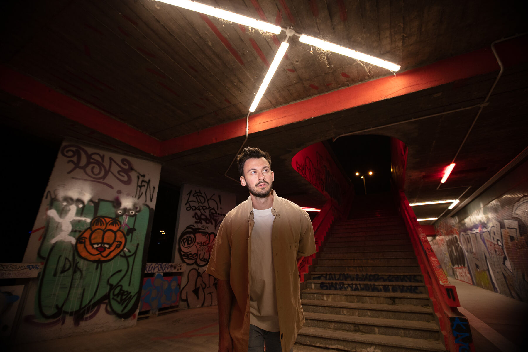 Bury walking through a graffiti underpass under fluorescent light
