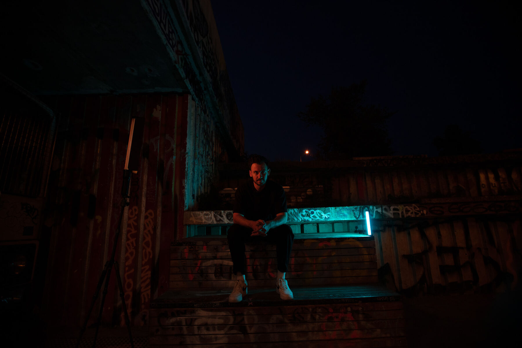 Bury sitting on graffiti steps lit in teal